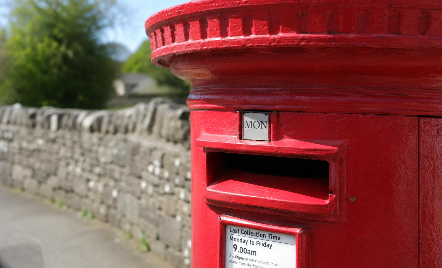 Red, English postbox in a rural scene.